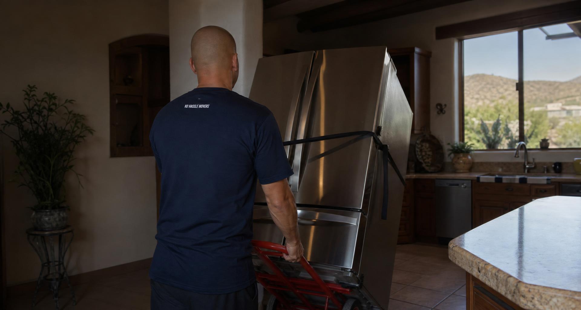 No Hassle Movers crew moving a refrigerator with a dolly and straps in a Tucson home